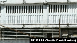 FOTO ARCHIVO. Reclusos permanecen detrás de una puerta enrejada en la prisión "Combinado del Este", en las afueras de La Habana, el 31 de marzo de 2004.
