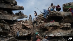 Ciudadanos de La Guaira alrededor de un edificio destruido por el terremoto del pasado 24 de junio, en Venezuela. (AP)