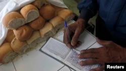 Un trabajador ("bodeguero") escribe en una libreta de racionamiento en La Habana. (REUTERS)