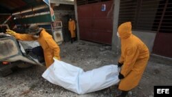 Miembros del personal de salud pública de Haití trasladan el cadavér de una víctima de cólera. Foto de Archivo