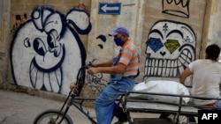 Un hombre en triciclo y con nasobuco recorre una calle de La Habana. (Yamil Lage/AFP)