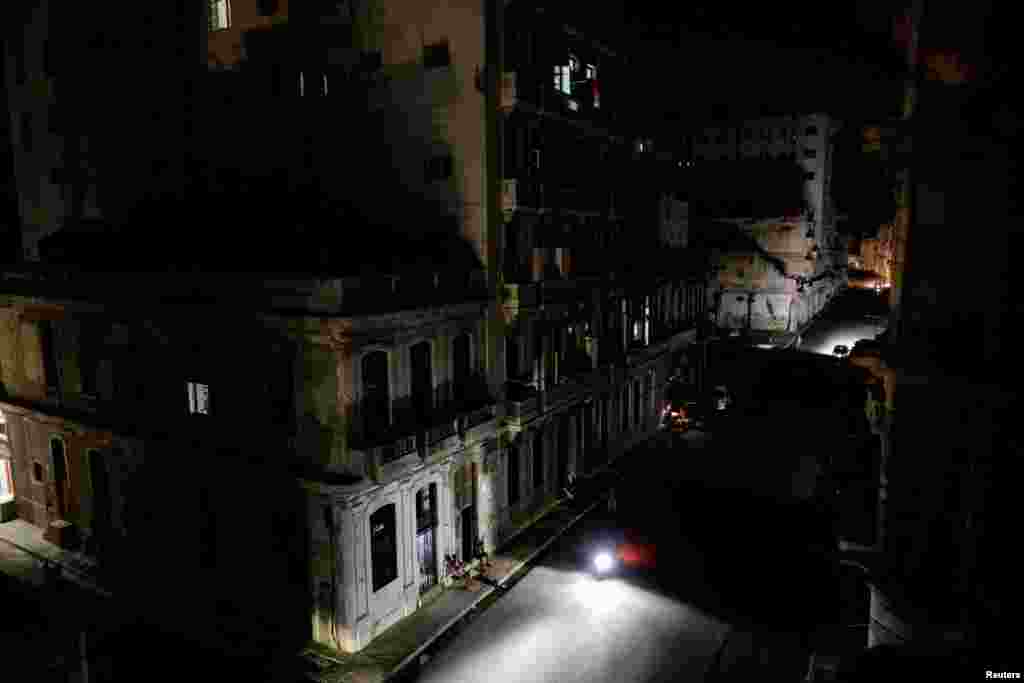 El faro de una motocicleta ilumina una calle oscura mientras los residentes permanecen sentados frente a sus edificios de apartamentos tras el colapso de la red eléctrica nacional de Cuba —el tercer apagón importante en nueve días—, en La Habana, Cuba, el 14 de julio de 2026. REUTERS/Norlys Perez