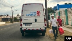 Empleados de una empresa estadounidense de envío de remesas de alimentos entregan bolsas de comida en un barrio de La Habana el 22 de mayo de 2024.
