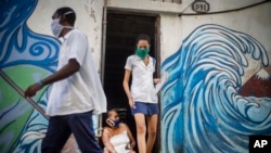 Dos trabajadores de salud provistos de mascarilas se retiran de un inmueble en La Habana tras verificar que la zona esta libre de COVID-19. (AP/Ramón Espinosa)