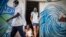 Dos trabajadores de salud provistos de mascarilas se retiran de un inmueble en La Habana tras verificar que la zona esta libre de COVID-19. (AP/Ramón Espinosa)