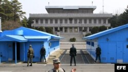 Soldados surcoreanos (de espaldas a la cámara) observan a un soldado norcoreano (al fondo, entre las columnas) en la zona desmilitarizada donde en 1953 se firmó el armisticio entre las dos coreas en Panmunjom (Corea del Sur) 