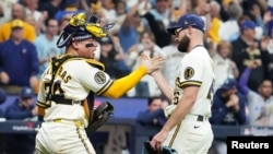 El catcher venezolano William Contreras felicita al relevista Aaron Ashby, tras la victoria el sábado de los Cerveceros en el segundo juego de la Serie Mundial.