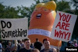 Manifestantes exhibieron un globo que representaba a un "bebé Trump" y carteles que decían "Haz algo", "Salva a nuestra ciudad" y "Tú eres la causa".
