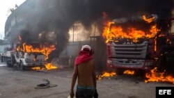 Un manifestante observa dos vehículos incendiándose en una protesta contra el Gobierno venezolano este lunes en Caracas.