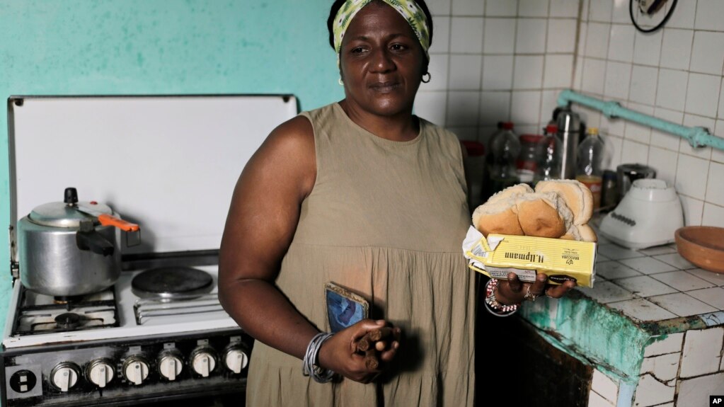 María de los Ángeles Pozo, una lavoratrice scolastica in pensione, posa per una foto nella sua cucina con alcuni alimenti della tessera annonaria, il 6 marzo 2024. (AP Photo/Ariel Ley)
