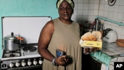 María de los Ángeles Pozo, trabajadora escolar jubilada, posa para una fotografía en su cocina con algunos de los alimentos de la libreta de racionamiento, el 6 de marzo de 2024. (Foto AP/Ariel Ley)