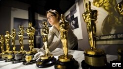 Una mujer coloca los premios de la academia de cine estadounidense.
