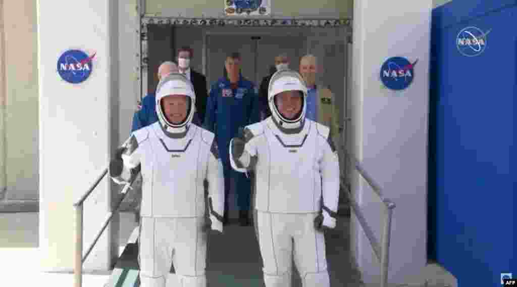 Los astronautas Bob Behnken (derecha) y Doug Hurley se dirigen hacia los vehículos que los transportaron a la rampa de lanzamiento de la cápsula SpaceX Crew Dragon, el 30 de mayo del 2020. (Foto AFP tomada de NASA TV)