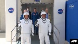Los astronautas Bob Behnken (derecha) y Doug Hurley se dirigen hacia los vehículos que los transportaron a la rampa de lanzamiento de la cápsula SpaceX Crew Dragon, el 30 de mayo del 2020. (Foto AFP tomada de NASA TV)