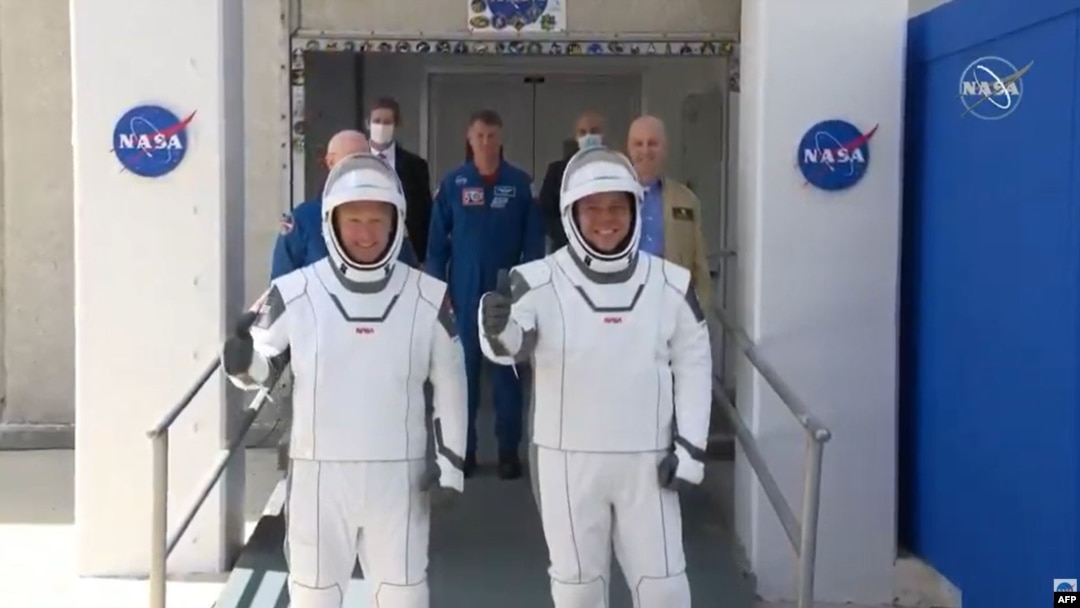 Los astronautas Bob Behnken (derecha) y Doug Hurley se dirigen hacia los vehículos que los transportaron a la rampa de lanzamiento de la cápsula SpaceX Crew Dragon, el 30 de mayo del 2020. (Foto AFP tomada de NASA TV)