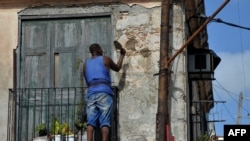 Un hombre repara la fachada de un viejo edificio en La Habana. 