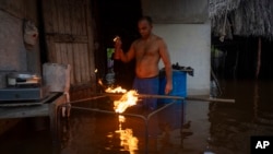 Un cubano enciende carbón para cocinar en su casa inundada tras el paso del huracán Helene en Artemisa / (Foto AP/Ramon Espinosa)