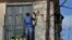 Un hombre repara la fachada de un viejo edificio en La Habana. 