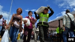 Un policía colombiano ayuda a venezolanos que regresan luego de hacer compras.