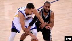 El jugador de los Golden State Warriors Stephen Curry (izda) lucha por el balón con Patty Mills (dcha), de los San Antonio Spurs. 