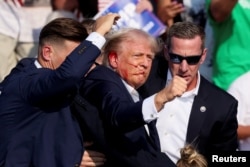 El ex presidente Donald Trump es asistido por personal de seguridad después de que se escucharon disparos durante un mitin de campaña en Butler, Pensilvania, el 13 de julio de 2024. REUTERS/Brendan McDermid