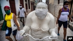 Transeúntes pasan junto a una de las estatuas de Xu Hongfei en La Habana, a la que alguien añadió un nasobuco. (AP/Ramon Espinosa)