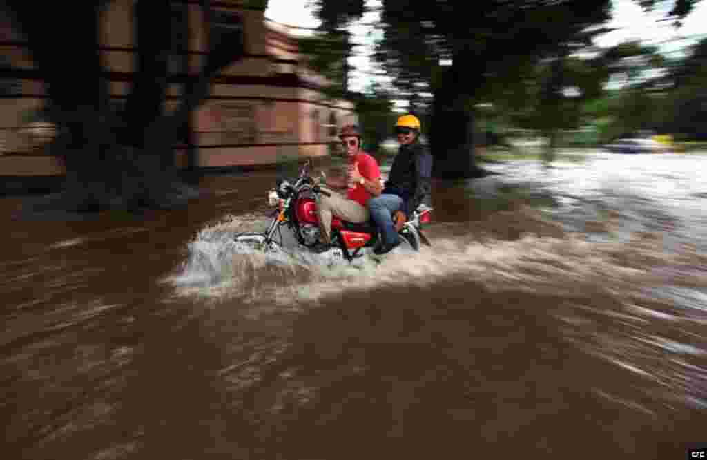 Dos hombres transitan en moto por una calle inundada hoy, viernes 29 de noviembre de 2013, en La Habana 