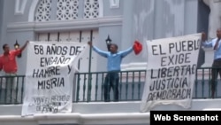Opositores enarbolan carteles en contra del Gobierno cubano en la catedral de Santiago de Cuba.