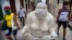 Transeúntes pasan junto a una de las estatuas de Xu Hongfei en La Habana, a la que alguien añadió un nasobuco. (AP/Ramon Espinosa)