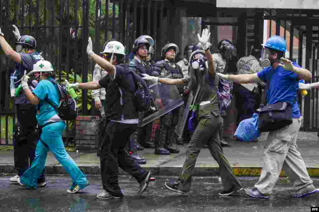 Un grupo de paramédicos voluntarios caminan con sus manos en alto en medio de los intentos de la Policía Nacional Bolivariana (GNB) por dispersar un grupo de manifestantes opositores al Gobierno.