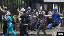 Un grupo de paramédicos voluntarios caminan con sus manos en alto en medio de los intentos de la Policía Nacional Bolivariana (GNB) por dispersar un grupo de manifestantes opositores al Gobierno.