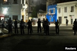 Oficiales de policía observan a residentes de un barrio de La Habana que protestan mientras su calle permanece sin electricidad. (Reuters/Norlys Perez)