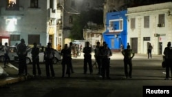 Oficiales de policía observan a residentes de un barrio de La Habana (no en la foto) que protestan mientras su calle permanece sin electricidad, el 21 de octubre de 2024. (Reuters/Norlys Perez).