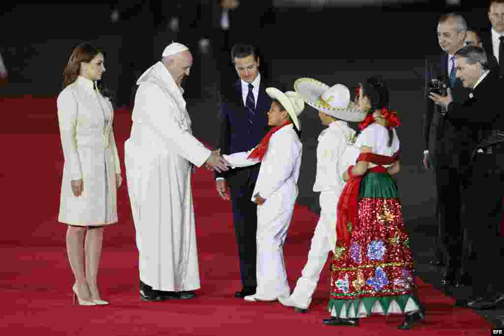 El papa Francisco es recibido por el presidente mexicano, Enrique Peña Nieto (c), la primera dama, Angélica Rivera (i), y un grupo de niños.