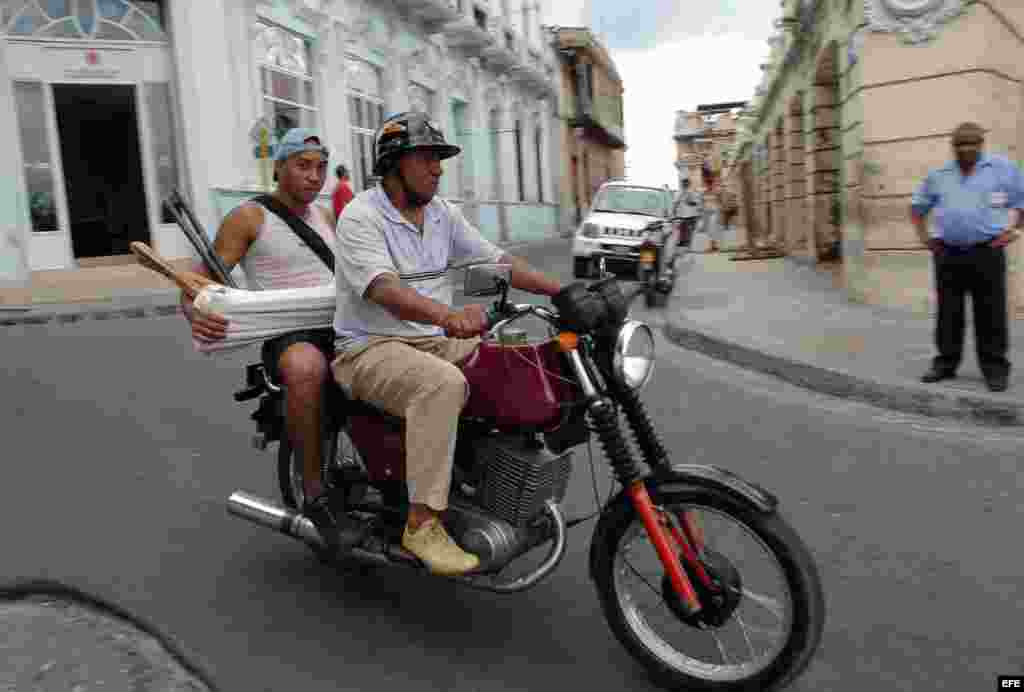 A man traveling on a motorbike taxi in the streets of Santiago de Cuba. Around 16,000 motorcycles of various makes, models and nationalities are on the streets every day as private taxis in Santiago de Cuba.