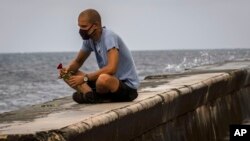 Un hombre echa una rosa al mar en el Malecón de La Habana, en medio de la pandemia de coronavirus. (AP/Ramon Espinosa)