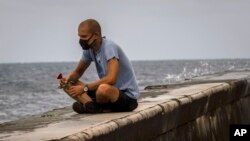 Un hombre echa una rosa al mar en el Malecón de La Habana en medio de la pandemia de coronavirus. (AP/Ramon Espinosa)