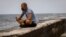 Un hombre echa una rosa al mar en el Malecón de La Habana, en medio de la pandemia de coronavirus. (AP/Ramon Espinosa)