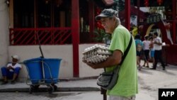 Un hombre camina por La Habana cargando cartones de huevos.