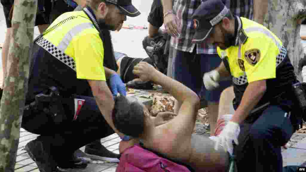Efectivos policiales atienden a una de las víctimas de un atropello masivo de una furgoneta que ha arrollado esta tarde a varias personas que paseaban por las Ramblas de Barcelona. Los Mossos d'Esquadra y los equipos de emergencias sanitarias han desplega