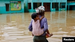 Un hombre lleva a su nieta en la espalda en un área inundada en la zona de Feni, Bangladesh. REUTERS/Mohammad Ponir Hossain