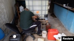 Un hombre llena un recipiente desde un tanque de almacenamiento que contiene gasolina importada para su venta en una vivienda particular, en La Habana, Cuba, el 2 de octubre de 2026. REUTERS/Ricardo Arduengo