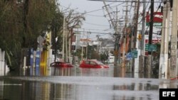 Dos automóviles flotan en una calle totalmente inundada en San Juan , Puerto Rico.