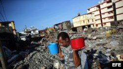 Cubanos recolectan agua tras el paso hace tres días del huracán Matthew en Baracoa.