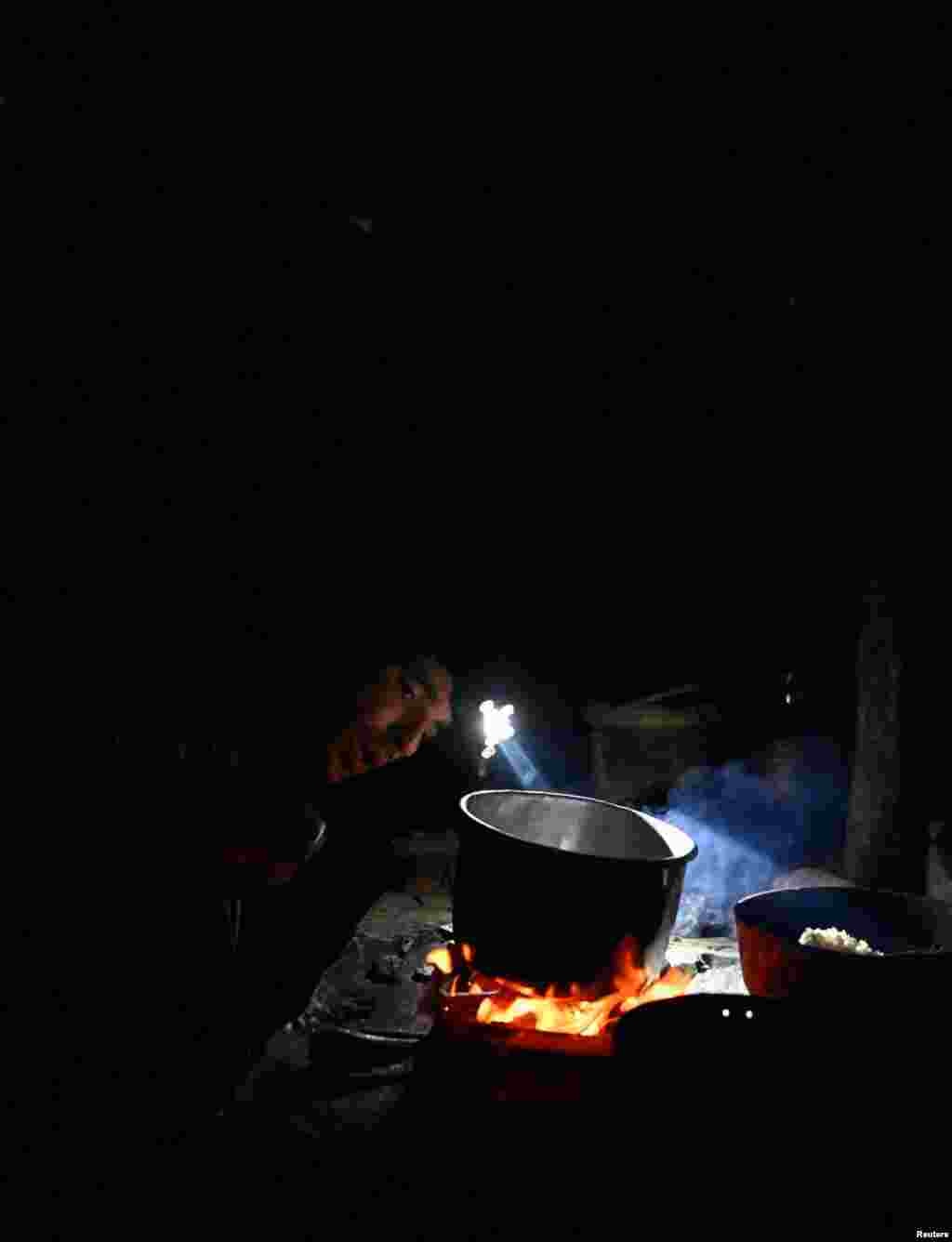 El pescador Yudel Ramos, de 30 años, utiliza una linterna frontal durante un apagón mientras sopla las brasas para calentar agua en una estufa de leña para bañarse, en Palpite, Ciénaga de Zapata, Cuba, el 7 de abril de 2026. REUTERS/Norlys Perez
