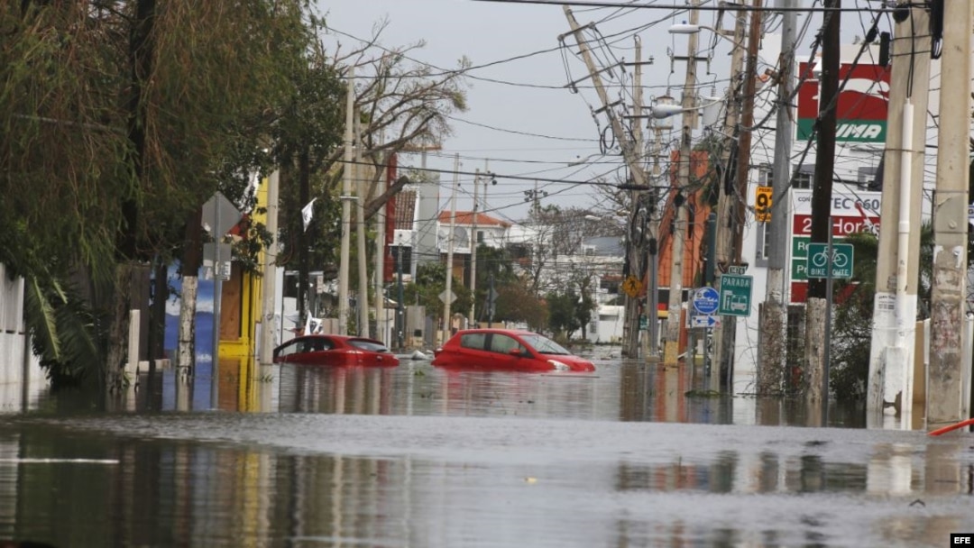 Dos automóviles flotan en una calle totalmente inundada en San Juan , Puerto Rico.