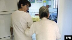 Una auxiliar acompaña a una enferma de alzheimer en el centro de día "La Pineda" en Castellón, España