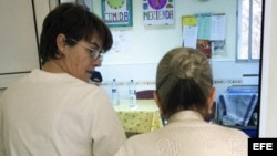 Una auxiliar acompaña al comedor a una enferma de alzheimer en el centro de día "La Pineda" en Castellón. 