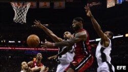 Los jugadores de los Spurs Tim Duncan (i) y Kawhi Leonard (d) disputan la bola con LeBron James (c) del Miami Heat. James fue prácticamente anulado por la fuerte defensa de San Antonio. 