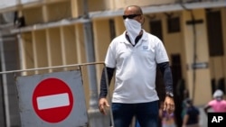 Un hombre con mascarilla frente a una calle cerrada al tráfico vehicular en La Habana. (AP/Ramon Espinosa)